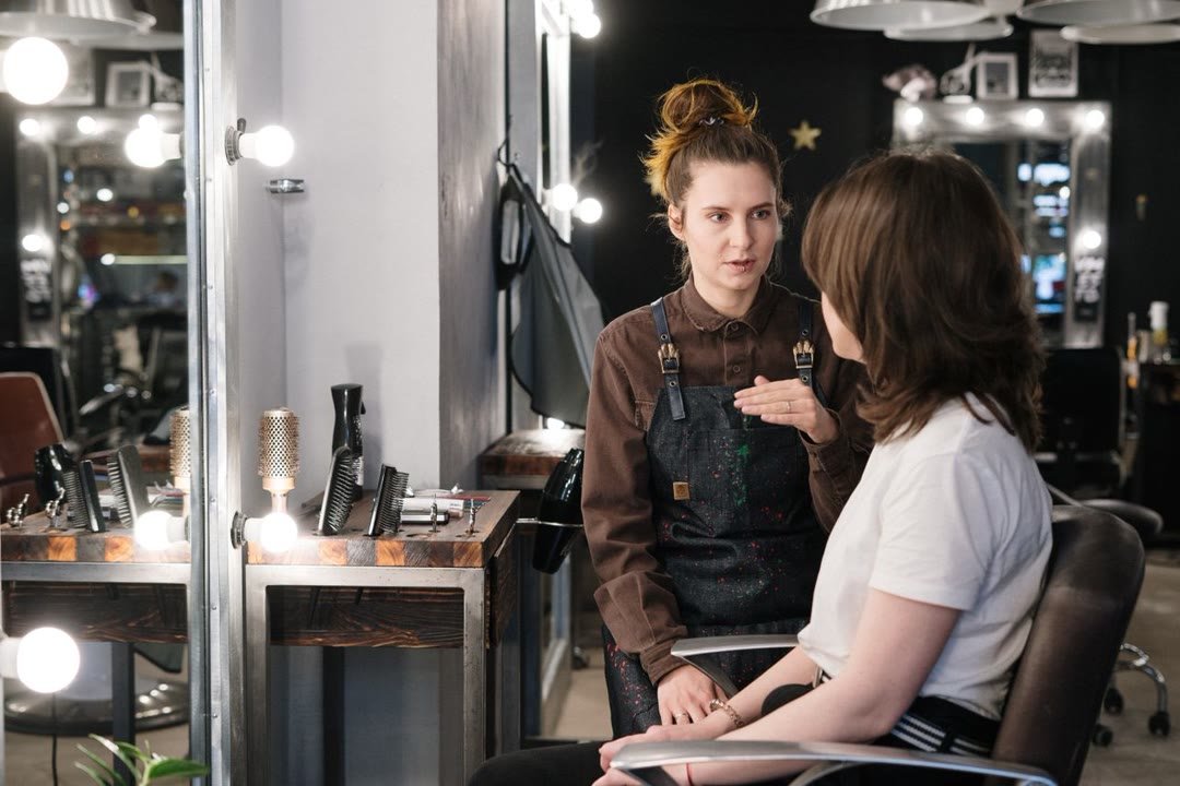 A stylist consulting with a client at a salon vanity mirror